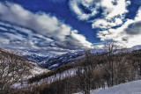 View of the mountains and snow-covered forests of Val d'Allos - La Foux from the Grands Prés snowshoe trail, blue sky in the background