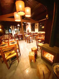 The restaurant's interior dining room, offering a comfortable atmosphere with wooden tables and chairs, tiled floors, and a wood-burning stove.