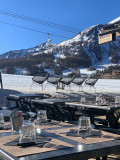Vue des pistes de ski et des montagnes depuis la terrasse ensoleillée de l'établissement, télésiège à proximité