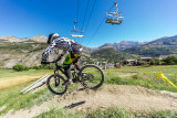 A mountain biker riding down a trail below the Clos Bertrand chairlift in Val d'Allos – Le Seignus in summer. The resort and mountains are visible in the background