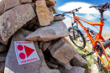 VTT situé à côté d'un cairn en pierre figurant un panneau de sentier de VTTAE 