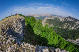 Panorama depuis un sommet, pic rocheux donnant sur une forêt de conifères, nombreuses montagnes en arrière-plan