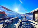 Terrasse ensoleillée du restaurant, tables et chaises, accès aux pistes enneigées, télésiège à proximité