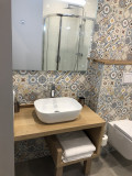 Salle de bains lumineuse, carrelage, évier, miroir et toilettes