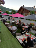 Outdoor terrace with artificial grass flooring, tables and chairs, parasols, village main street