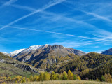 Panorama dégagé sur une vallée de montagne colorée et boisée. Les sommets des montagnes en arrière-plan sont enneigées
