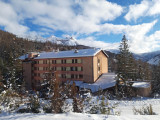 Vue extérieur du centre de vacances, bâtiment sur plusieurs étages au milieu des montagnes enneigées