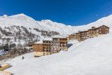 Vue de côté de la résidence, bâtiment sur plusieurs étages, neige autour du bâtiment et vue de la station