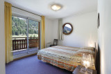 Chambre à coucher d'appartement avec lit double, fenêtre hublot, porte-fenêtre donnant sur balcon