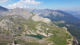 L'un des lacs de l'Encombrette, situé au sommet d'un promontoire rocheux avec végétation éparse. Forêts visibles en contrebas