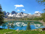 Le Lac d'Allos en fin de printemps, végétation verdoyante autour du lac, montagnes dites têtes du Lac en arrière-plan avec neige subsistante