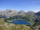 Panorama du lac d'Allos vu depuis le col de l'Encombrette, grand lac bleu entouré de forêts de conifères et de montagnes