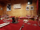 The restaurant's interior featuring wooden decor, warm-looking tables and chairs, and old portraits and photos on the walls.