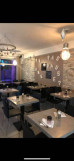 Bright and modern restaurant dining room with tables and chairs, window at the back overlooking the shopping arcade