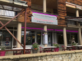 Restaurant front with outdoor terrace furnished with tables and chairs. Sign with the inscription : 