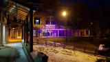 Front of the late-night restaurant with an outdoor terrace furnished with tables and chairs. Sign with the inscription: 