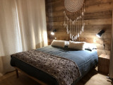 Bright bedroom with double bed, wooden furniture, window and curtains