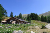 Vue du refuge-restaurant, maison en bois au milieu de la végétation, terrasse, tables et chaises