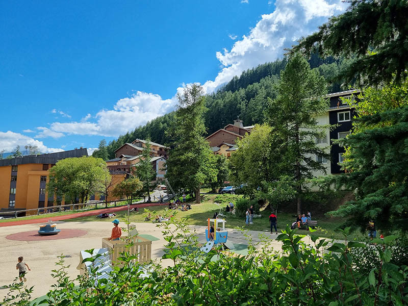 Children's playground in a relaxing setting, trees, benches, mountain views in the background
