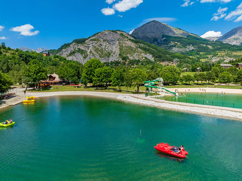 Aperçu des deux bassins du parc de loisirs d'Allos, gros plan sur le bassin aux pédalos, situé dans un cadre naturel avec montagnes boisées en arrière-plan - © R Palomba office de tourisme du Val d'Allos Aperçu des deux bassins du parc de loisirs d'Allos, gros plan sur le bassin aux pédalos, situé dans un cadre naturel avec montagnes boisées en arrière-plan