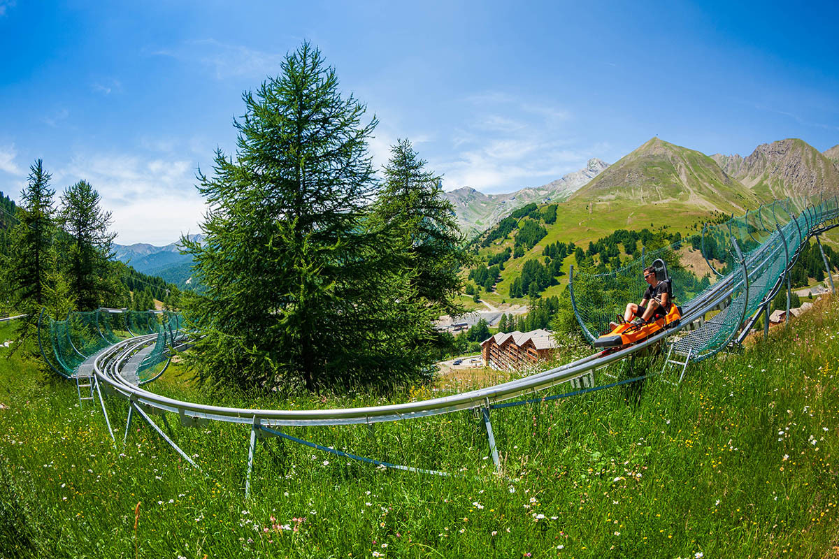 Luge sur rail Verdon Express, nacelle deux places, série de virages en épingle dans un cadre de végétation, vue dégagée sur les montagnes environnantes