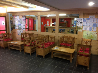 Hall d'entrée de la résidence, tables et chaises en bois, panneaux d'affichages, réception.