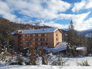 Vue extérieur du centre de vacances, bâtiment sur plusieurs étages au milieu des montagnes enneigées - © Rochecline Vue extérieur du centre de vacances, bâtiment sur plusieurs étages au milieu des montagnes enneigées