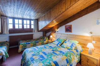 Grande chambre à coucher lumineuse sous combles, avec lit double et lits simples, décoration en lambris et ameublement bois, fenêtres - © F Hartl Grande chambre à coucher lumineuse sous combles, avec lit double et lits simples, décoration en lambris et ameublement bois, fenêtres