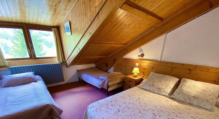 Grande chambre à coucher lumineuse sous combles avec lit double et lits simples, décoration en lambris et ameublement bois, fenêtres - © office de tourisme du Val d'Allos AG Grande chambre à coucher lumineuse sous combles avec lit double et lits simples, décoration en lambris et ameublement bois, fenêtres