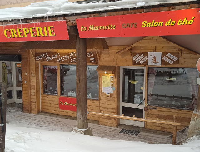 Devanture de la crêperie, façade vitrée avec spécialités affichées :