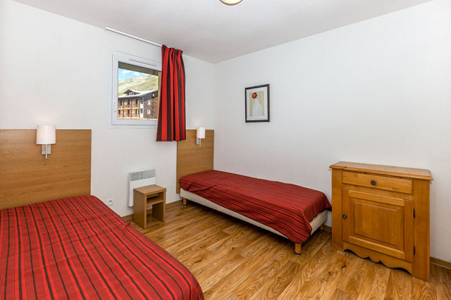 Apartment bedroom with double bed and single bed, wooden furniture, window