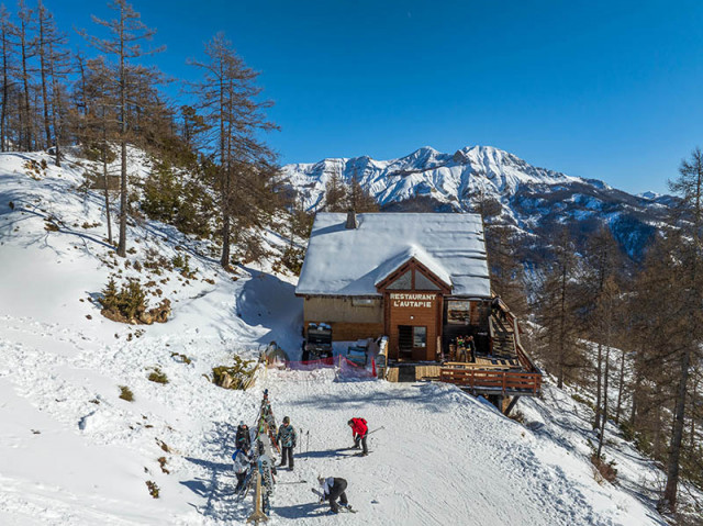 Vue du restaurant d'altitude, chalet en bois et pierre au milieu des montagnes enneigées, terrasse en bois
