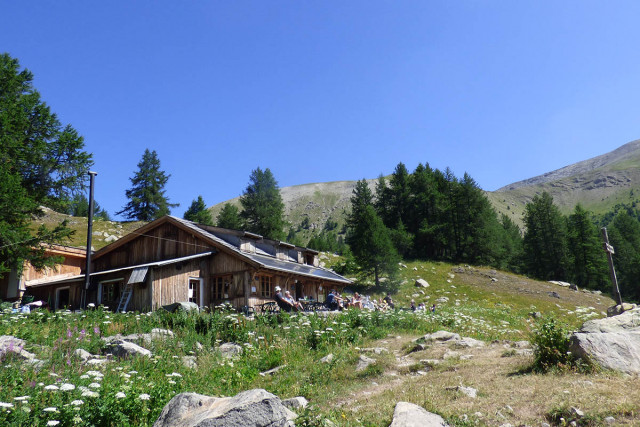 View of the refuge-restaurant, a wooden house in the middle of the vegetation, terrace, tables and chairs