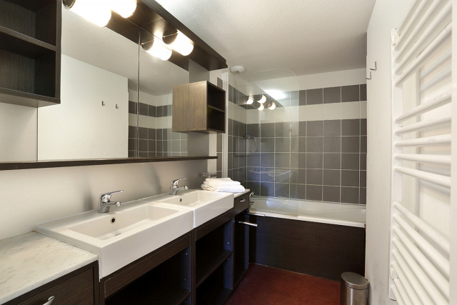Modern apartment bathrooms with bathtub, sinks, and mirrors