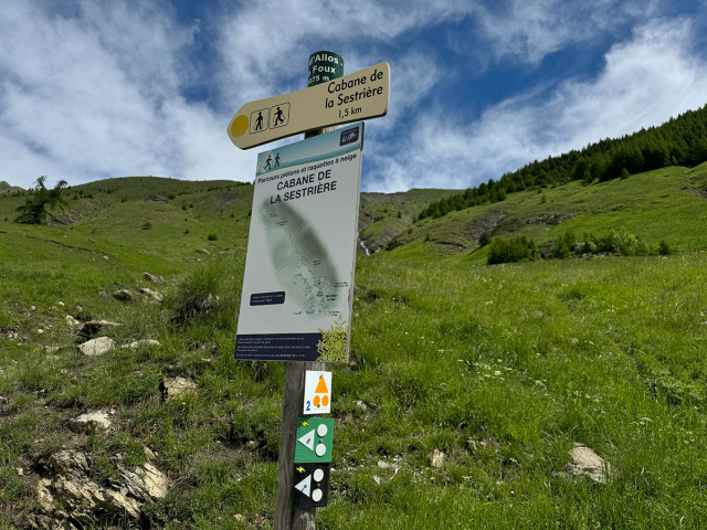 Signpost for the Sources du Verdon e-mountain bike route, located in the middle of a green mountain valley