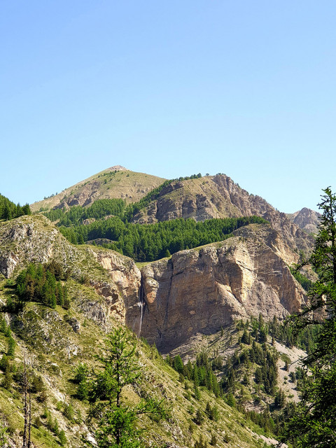 A distant view of the Pich waterfall, cascading down a rocky crevice, surrounded by forests both above and below - © B Courbon A distant view of the Pich waterfall, cascading down a rocky crevice, surrounded by forests both above and below