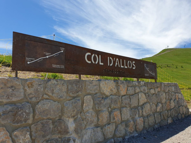 A rectangular Corten steel sign located at the summit of the Col d'Allos, at an altitude of 2,247 metres, showing the various stages of the route: Barcelonnette, Les Agneliers, the Col d'Allos