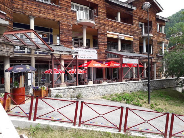 View of the restaurant from outside the shopping mall. Outdoor terrace with parasol. Sign with the inscription: 