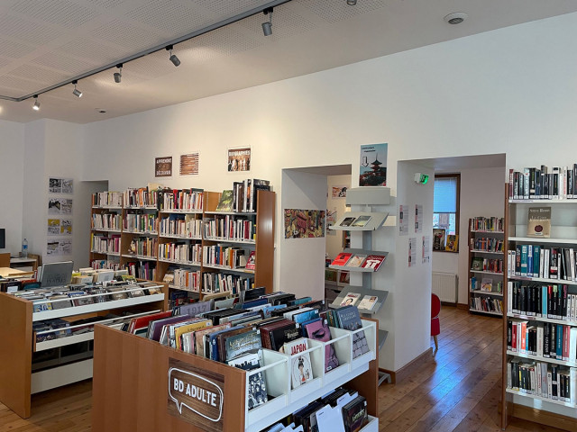 Salle de médiathèque, meubles de rangements et bibliothèques comprenant romans, BD, albums, romans, DVDs, romans graphiques, ordinateur. Ouvrages rangés par catégories - © Manon Fivaz Salle de médiathèque, meubles de rangements et bibliothèques comprenant romans, BD, albums, romans, DVDs, romans graphiques, ordinateur. Ouvrages rangés par catégories