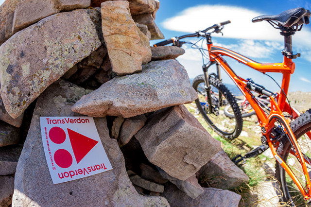 VTT situé à côté d'un cairn en pierre figurant un panneau de sentier de VTTAE 