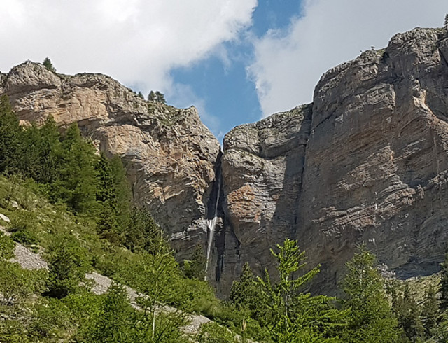 Vue de la cascade du Pich, située dans une crevasse rocheuse à côté d'une forêt de conifères - © B Courbon Vue de la cascade du Pich, située dans une crevasse rocheuse à côté d'une forêt de conifères