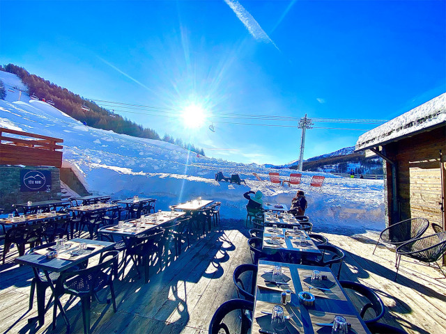 Terrasse ensoleillée du restaurant, tables et chaises, accès aux pistes enneigées, télésiège à proximité