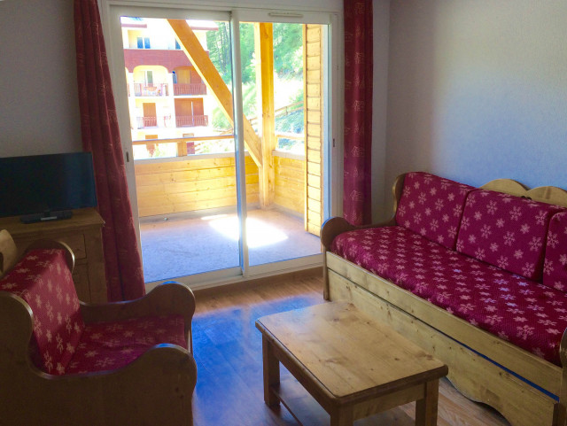 Bright apartment living room with sofa, armchair, coffee table, French doors opening onto a terrace