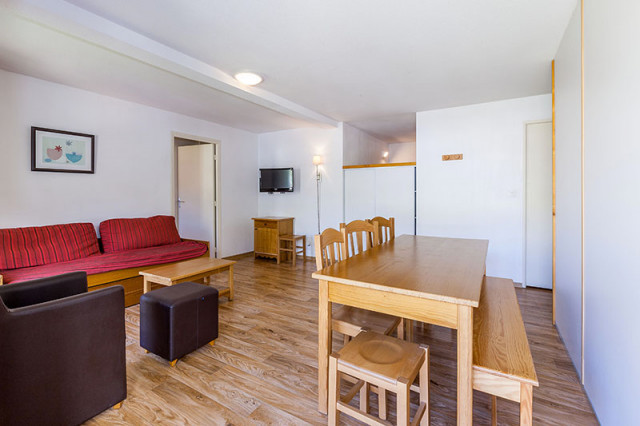 Séjour lumineux d'appartement avec canapé, fauteuil, table à manger, TV, séparations vers autres espaces - © Les cimes du Val d'Allos Séjour lumineux d'appartement avec canapé, fauteuil, table à manger, TV, séparations vers autres espaces