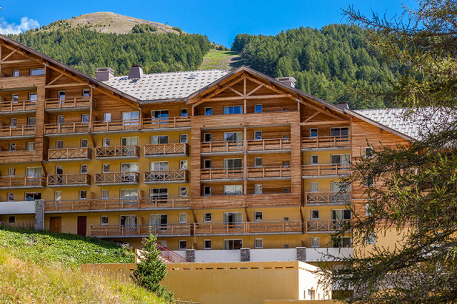 Vue de face de la résidence, bâtiment en bois sur plusieurs étages, montagnes en arrière-plan - © Les cimes du Val d'Allos Vue de face de la résidence, bâtiment en bois sur plusieurs étages, montagnes en arrière-plan