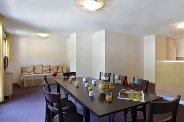 Salon d'appartement avec table à manger, canapé, TV, ameublement bois, fenêtre