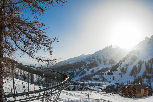 Luge sur rail Verdon Express, nacelle deux places, série de virages en épingle dans un paysage enneigé, vue dégagée sur les montagnes enneigées environnantes