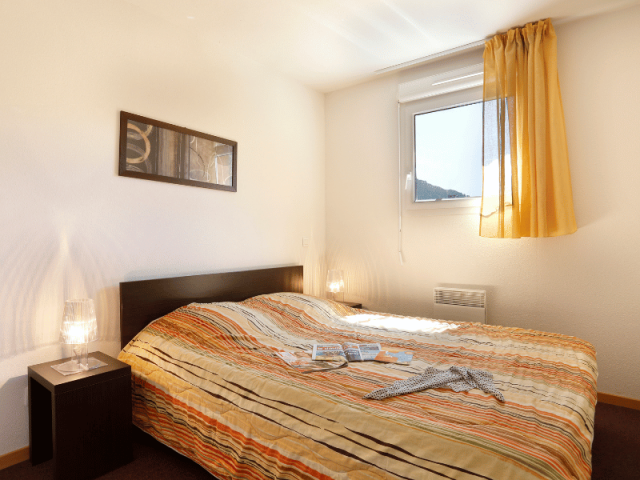 Apartment bedroom with double bed, porthole window, French doors opening onto a balcony