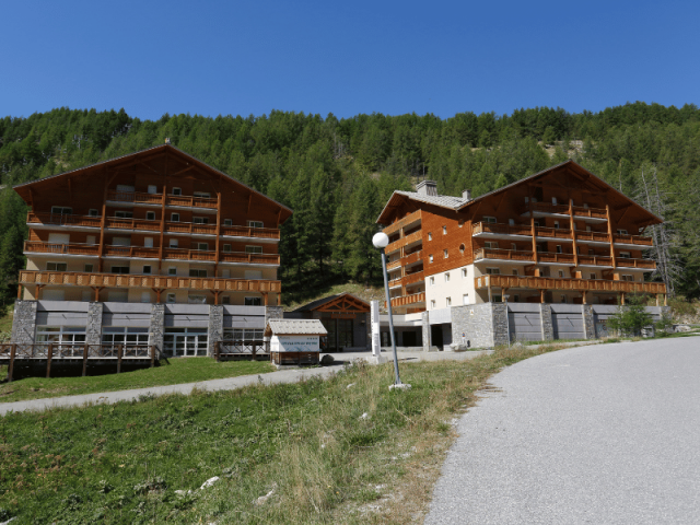 View of the residence: two multi-story buildings connected by a central wing with a reception area, mountain setting