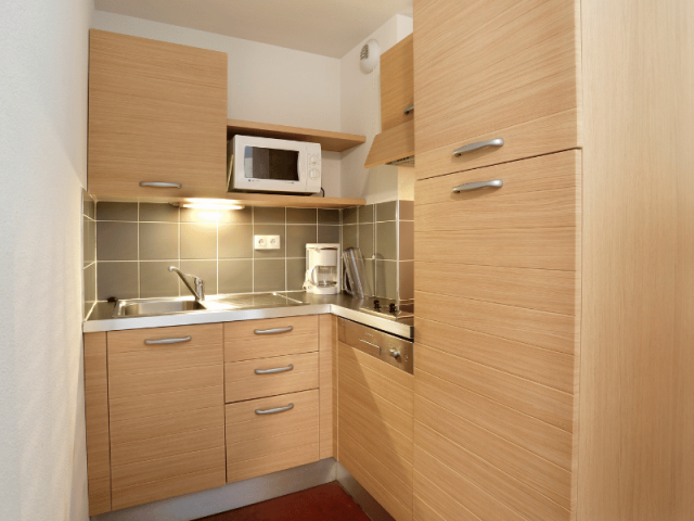 Kitchenette in a housing for 2 to 6 people, equipped with a microwave, a coffee machine, and an induction hob